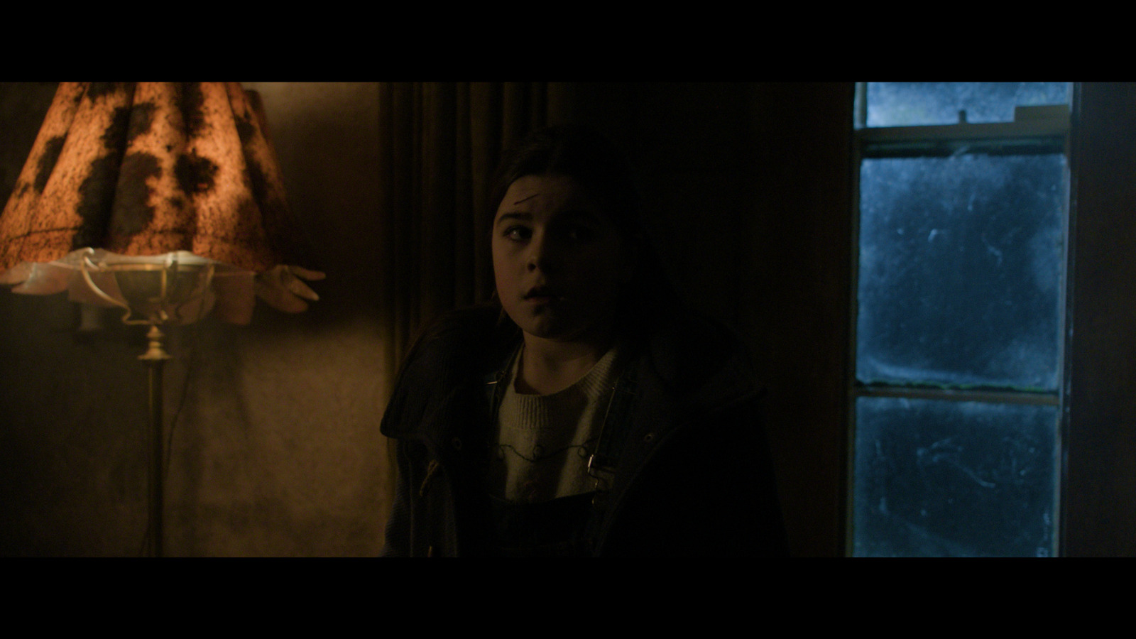 A young girl stares in horror at something insidious beyond our view.