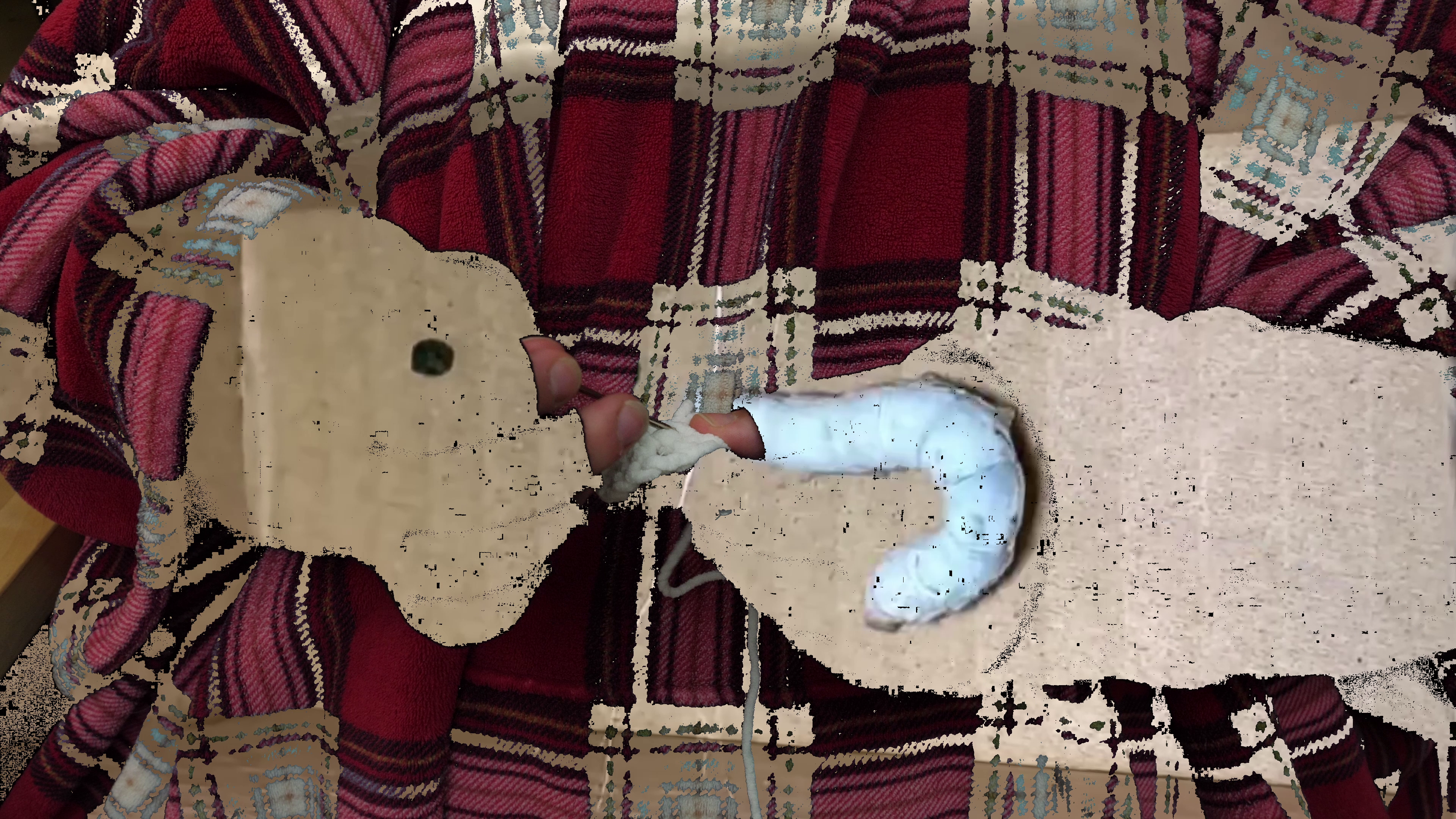 Logan Valentine sewing in the ends of the first round of crochet in making the cocoon. Their hands and a part of their clothes have been keyed out and replaced with a video of a silk moth making a cocoon.