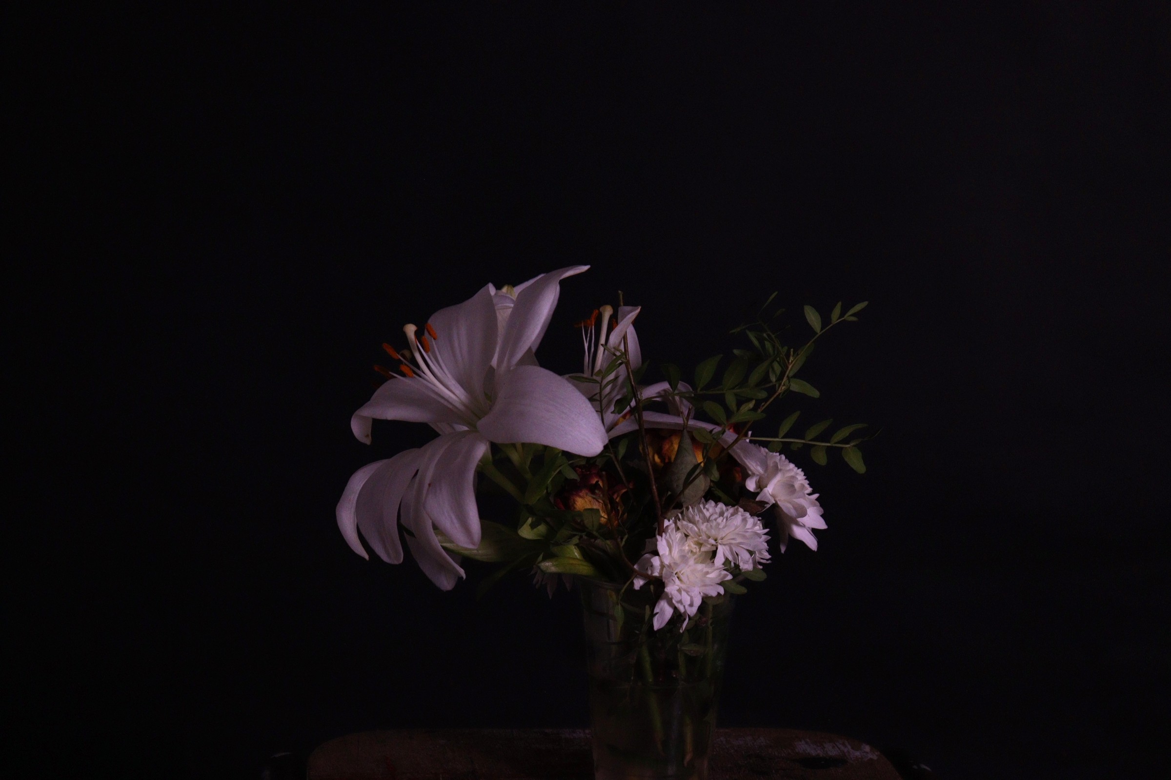 Lilies lit softly in the dark, a quiet nod to death