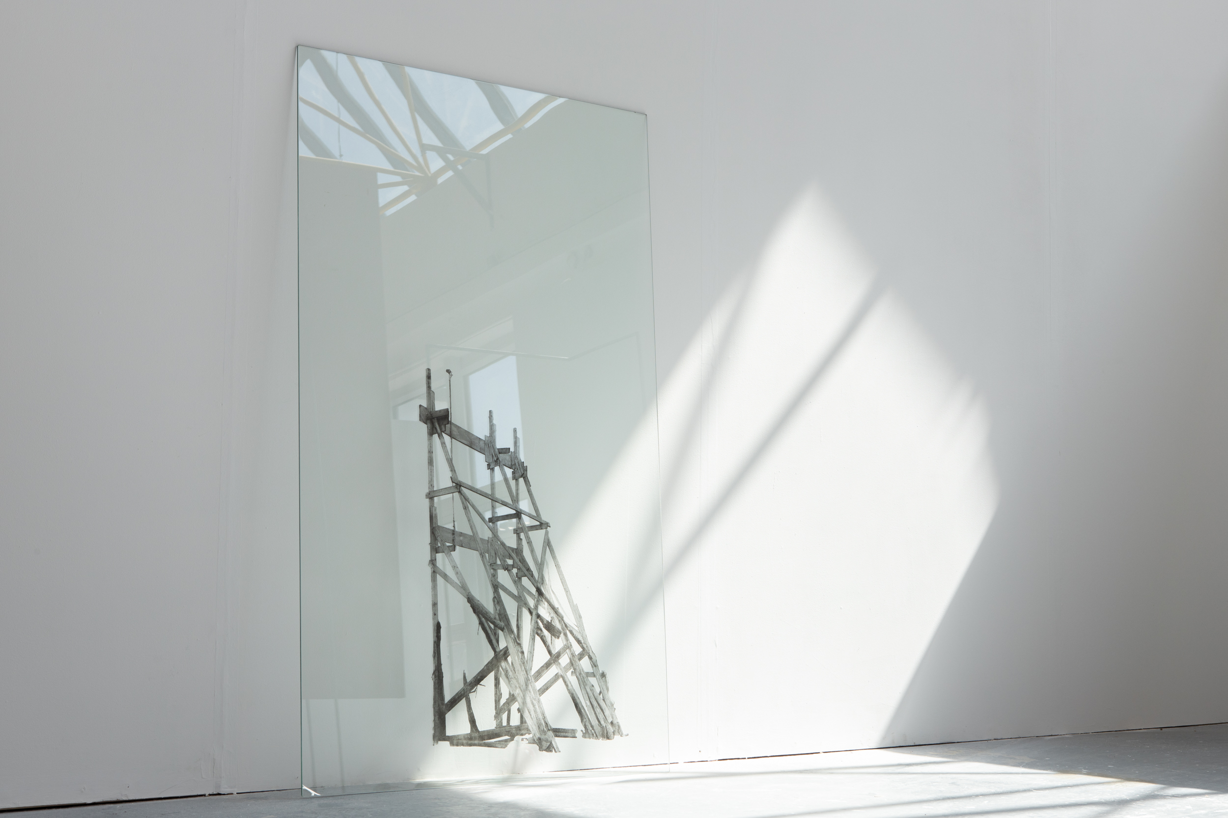 A wooden architectural support structure screenprinted onto glass. The glass leans against a white wall