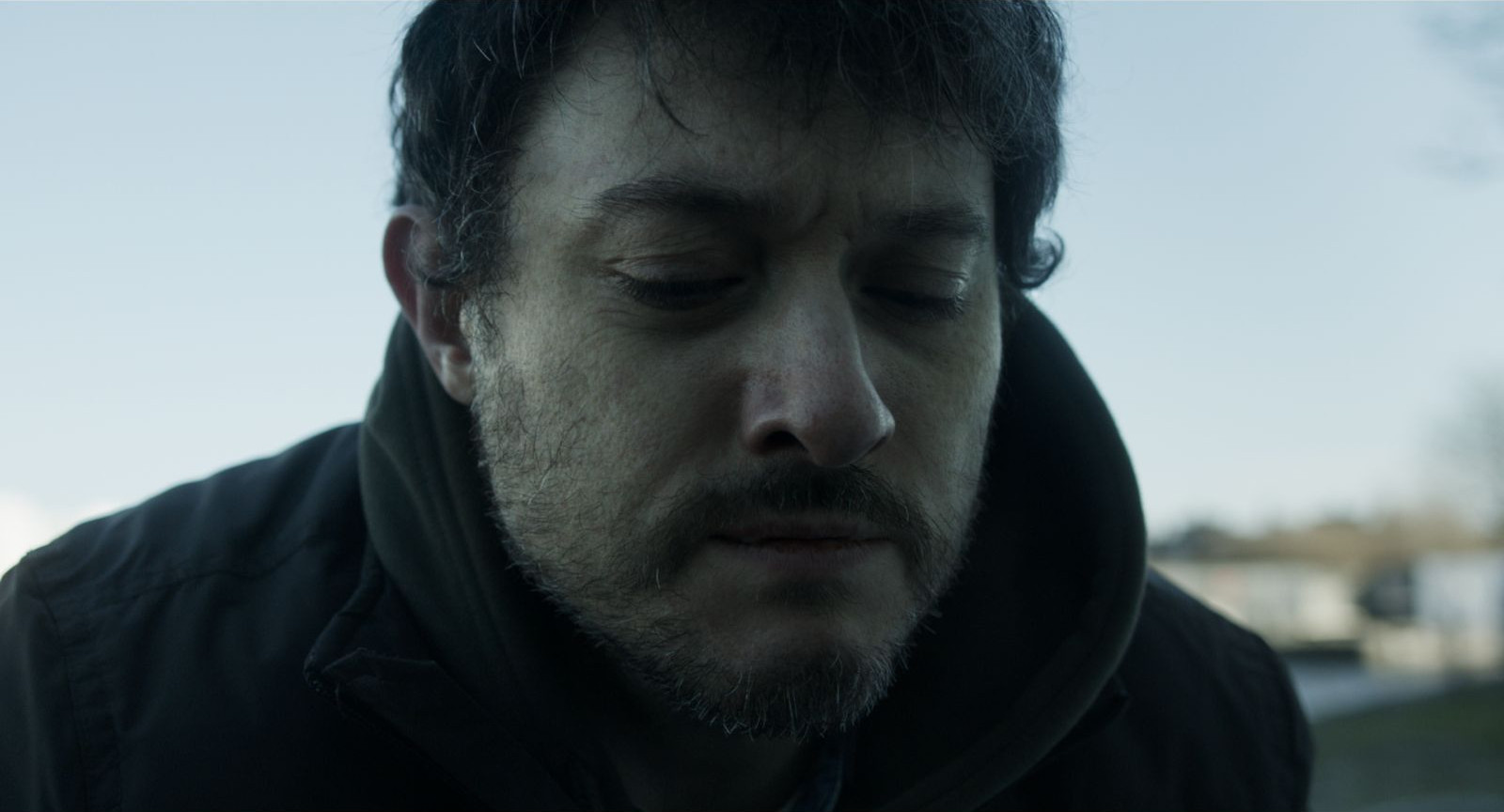 Still from "At What Cost?", showing the protagonist holding back tears