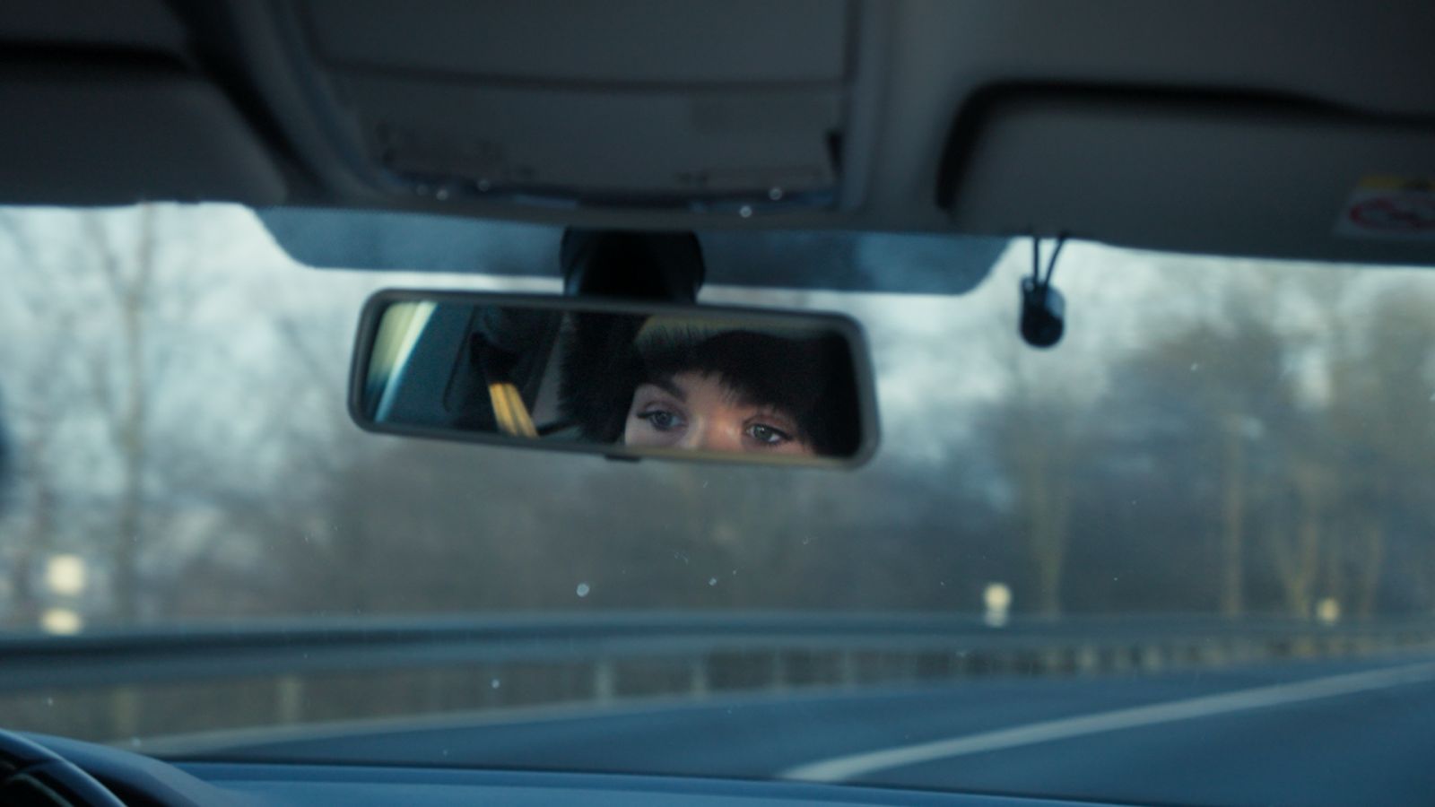 We are in the back of the car and see Anna (the contributors) eyes through the rearview mirror