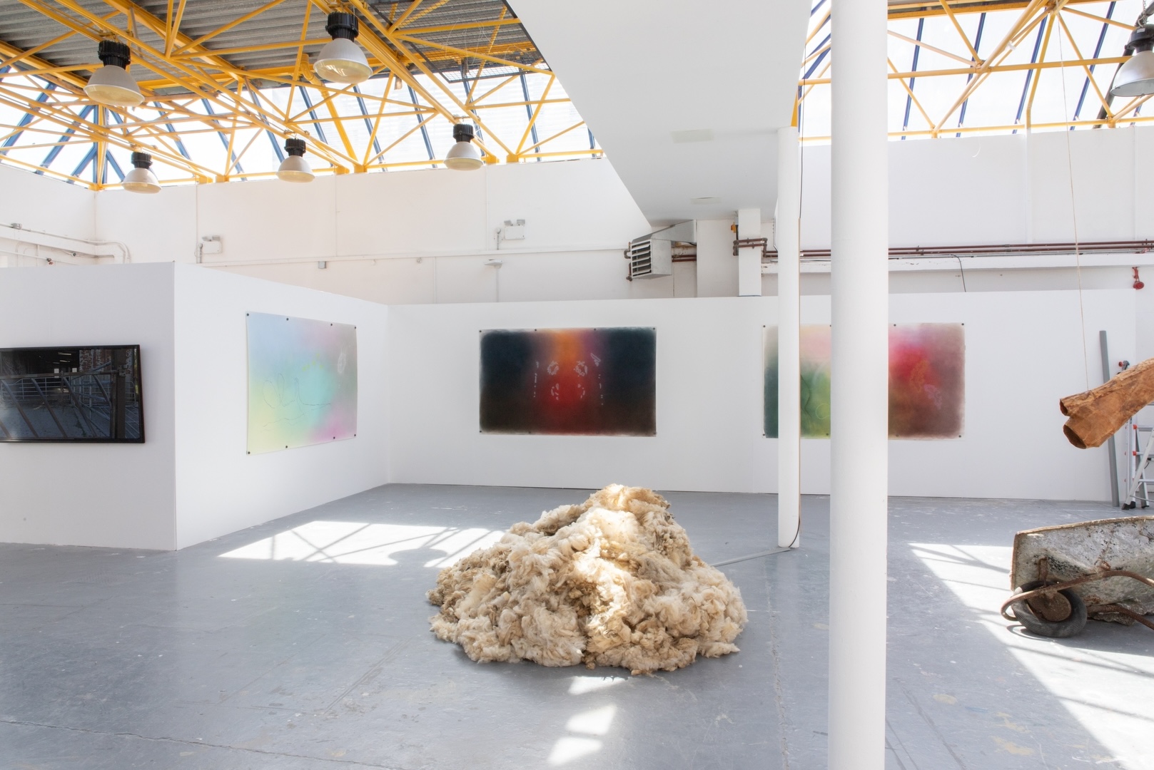 install view of monitor on far left, mound of wool in centre and wheelbarrow on side to right