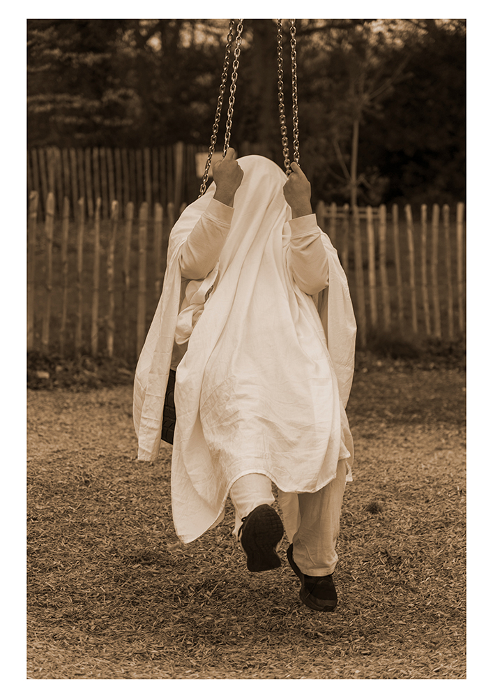A person in a white sheet sitting on a swing