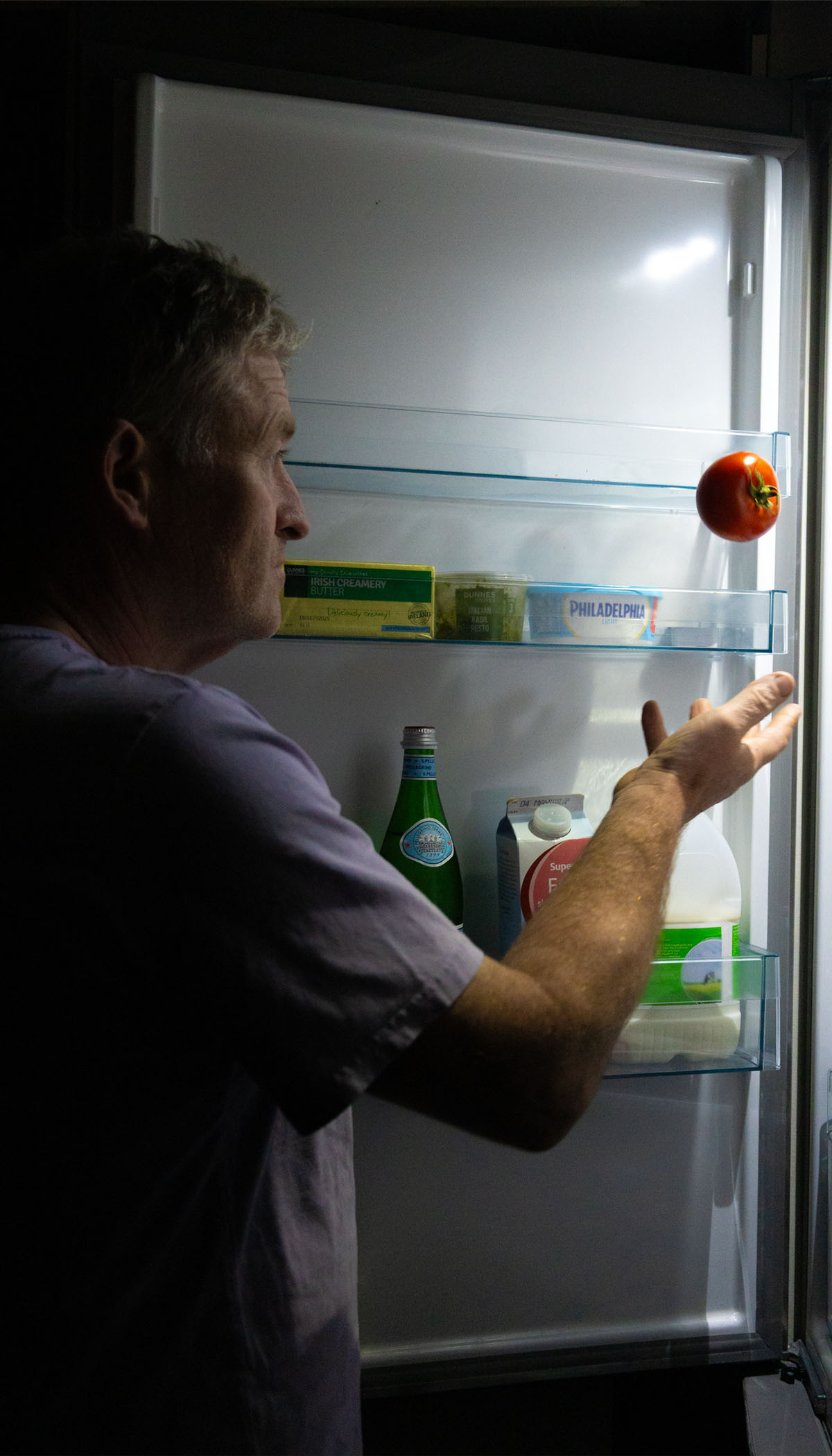 Father getting tomato from the fridge