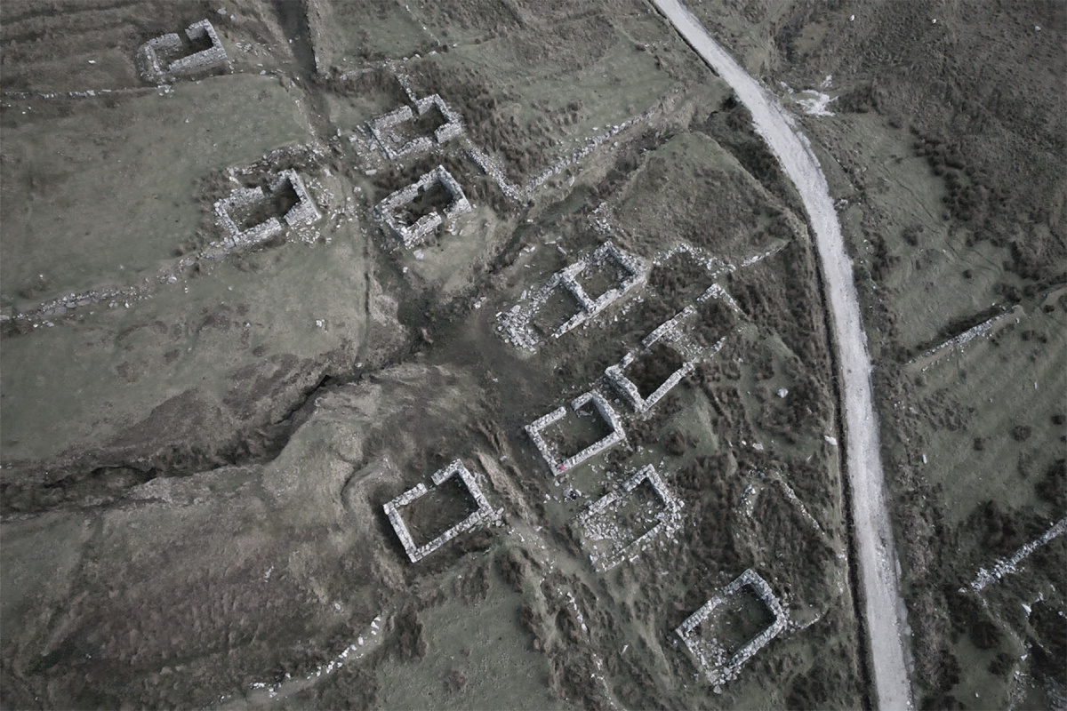 a drone image of approximately 10 stone cottages with a stone road running alongside