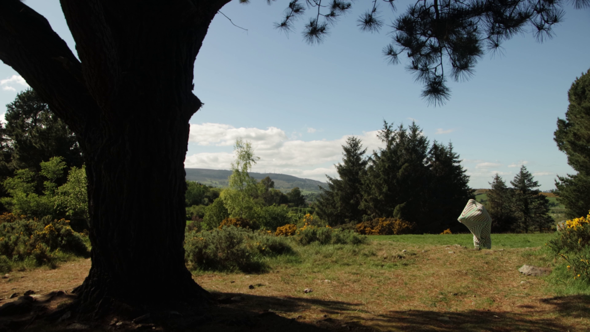 Logan Valentine in a Crocheted Cocoon in the distance, attempting to push their way out of it