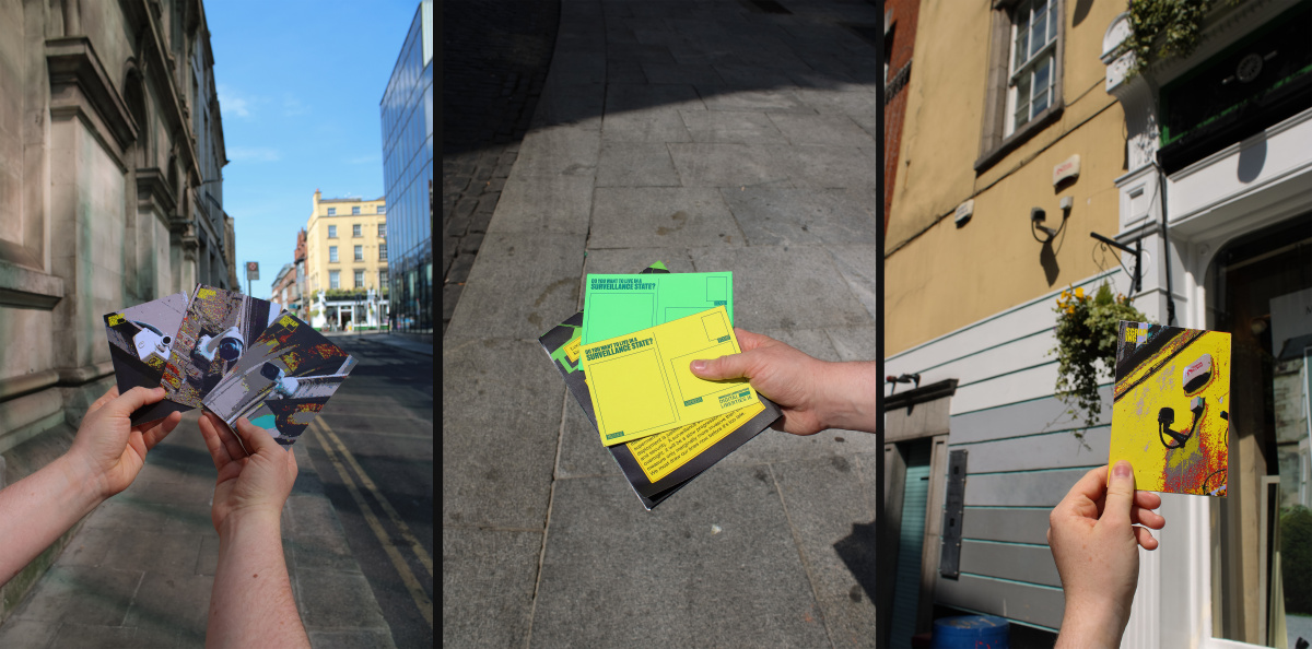 postcards photographed on an urban street, postcards have pixelated colourful photographs on surveillance cameras on them
