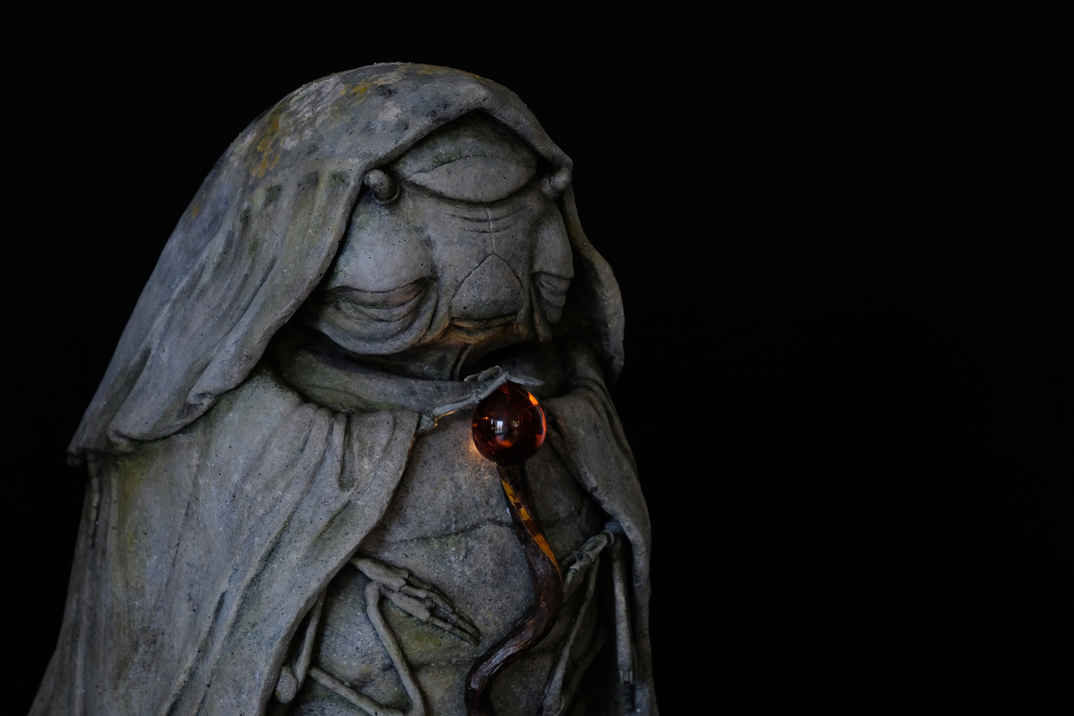 A photo of a stone-effect statue with glowing staff