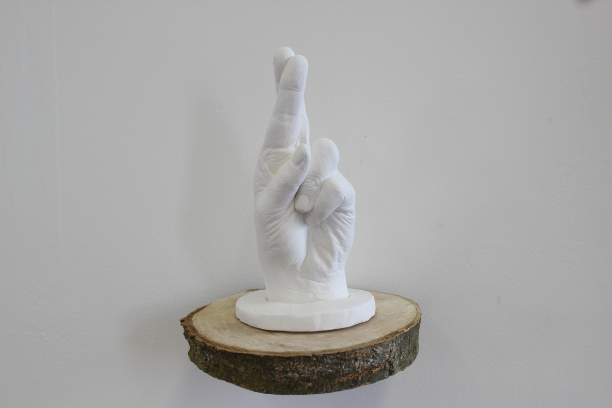 **Holding Hope**, 2026, Hand cast in Plaster, 20cm x 11cm approx. on a natural tree slice