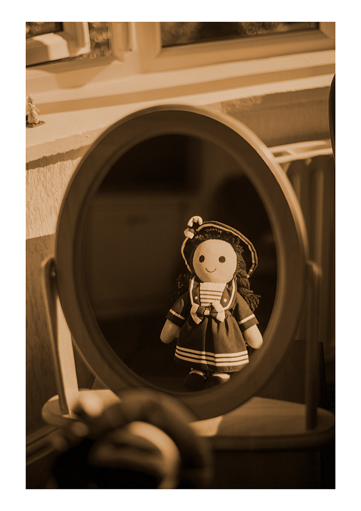 A rag doll in a sailor costume reflected in a mirror