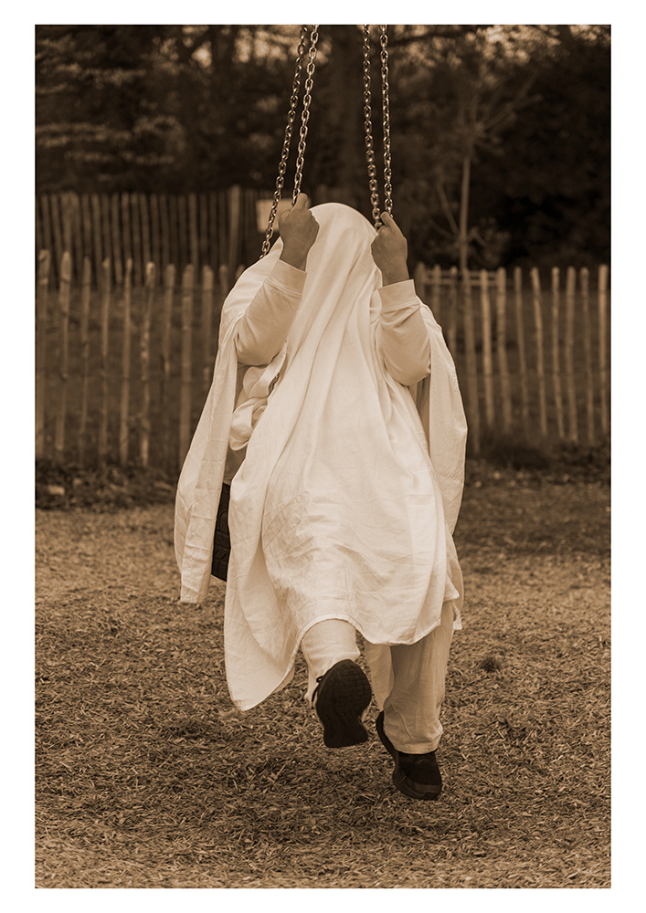 A person in a white sheet sitting on a swing
