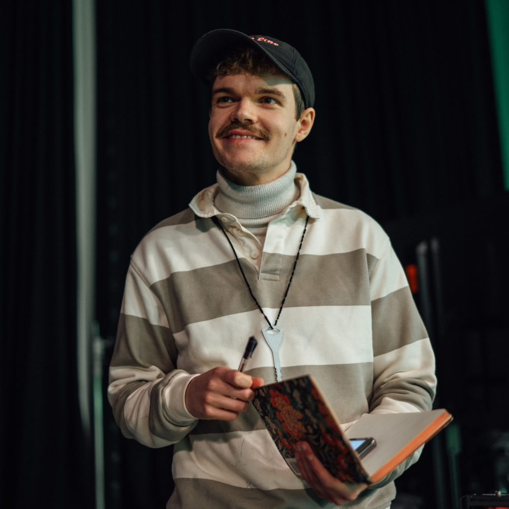 An image of Áindréas Fallon Verbruggen with a phone and notebook on the set of 'City Upon A Hill'
