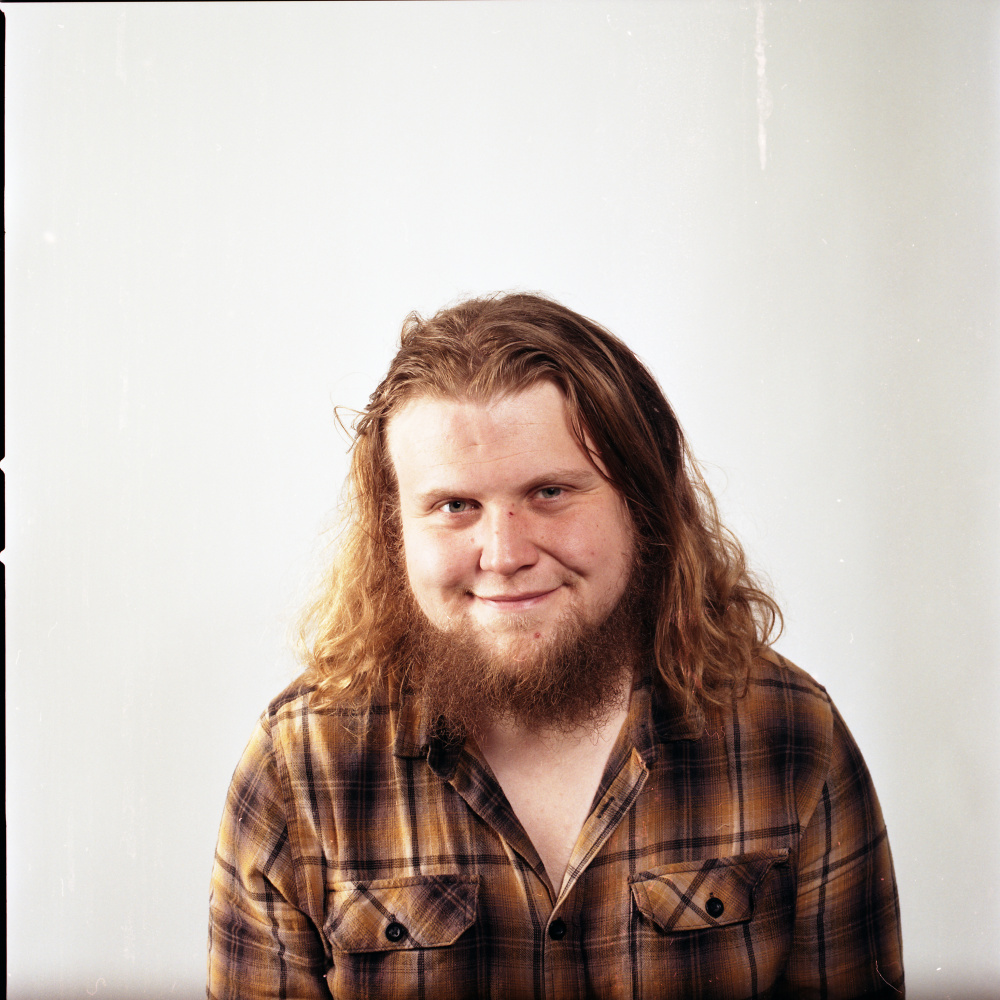 young bearded man with long blonde hair on a white background